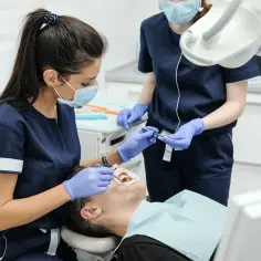 Dentystka wykonuje zabieg. Dowiedz się, jaka jest usuwanie zębów pod narkozą cena.