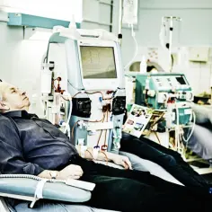 Starszy mężczyzna odpoczywa podczas zabiegu hemodializy, podłączony do aparatury medycznej.
