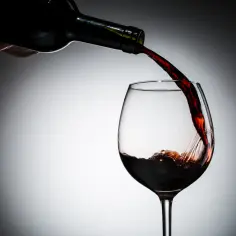 Czerwone wino leje się z butelki do kieliszka. Czy wino jest zdrowe? To pytanie zadaje sobie wielu.