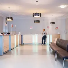Recepcja w nowoczesnej klinice medycznej z poczekalnią i numerkami.