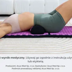 Osoba leży na macie akupresurowej z wałkiem pod kręgosłupem, łagodząc bóle kręgosłupa.