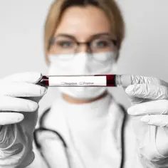 Lekarz w rękawiczkach trzyma probówkę z krwią, na której widnieje napis "Negative" i "Positive". To ważny moment w diagnostyce, gdy pojawiają się pierwsze objawy HIV.