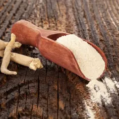 Korzeń ashwagandhy i jej proszek na drewnianym tle. Czy ashwagandha jest szkodliwa? Zazwyczaj nie, ale warto skonsultować się z lekarzem.