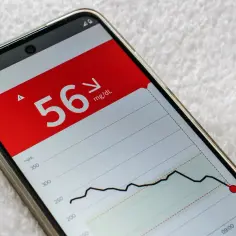 Niski poziom glukozy 56 mg/dL na ekranie telefonu, wskazujący na osłabienie. ICD-10 może pomóc w diagnozie.