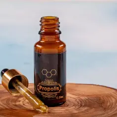 Propolis w kroplach na drewnianym plastrze. Dowiedz się, jak stosować propolis na jelita, by wesprzeć ich zdrowie.