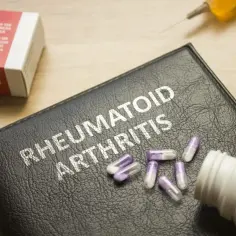Leczenie biologiczne RZS: kapsułki, strzykawka i pudełko leków na czarnym notesie z napisem "Rheumatoid Arthritis".