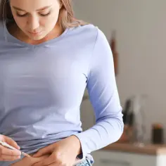 Kobieta wykonuje zastrzyk z insuliną, przygotowując się do życia po przeszczepie trzustki.