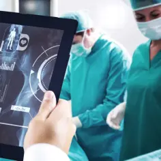 Chirurg analizuje na tablecie obraz stawu biodrowego, szukając informacji o bezinwazyjna operacja stawu biodrowego cena.