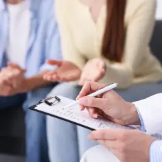 Para omawia z lekarzem program in vitro. Lekarz notuje informacje na karcie pacjenta.