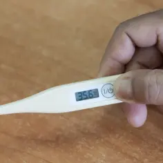 Dłoń trzyma termometr pokazujący 35.6°C. Czy to objaw niskiej temperatury przy covid?