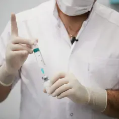 Lekarz w białym kitlu i rękawiczkach przygotowuje zastrzyk. To może być część terapii, np. chemiczna kastracja.