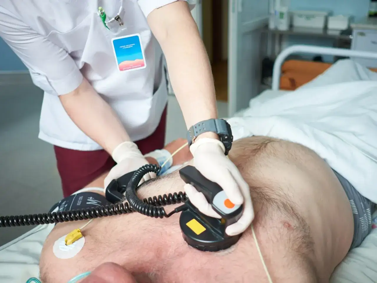 Ratownik medyczny wykonuje kardiowersję, przykłada elektrody defibrylatora do klatki piersiowej pacjenta, by przywrócić prawidłowy rytm serca.