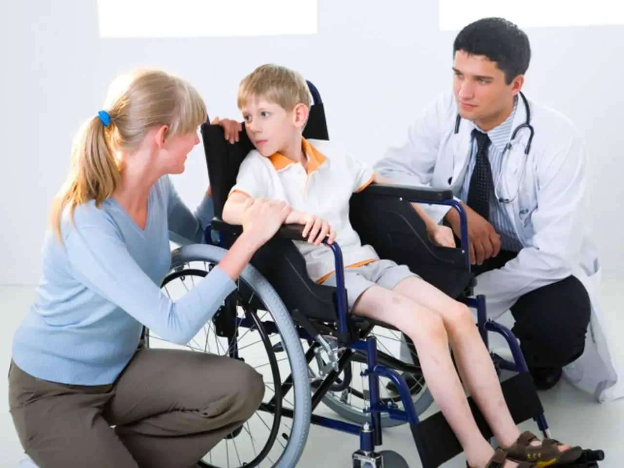 Chłopiec z dystrofią mięśniową Duchenne'a w wózku inwalidzkim rozmawia z matką i lekarzem.