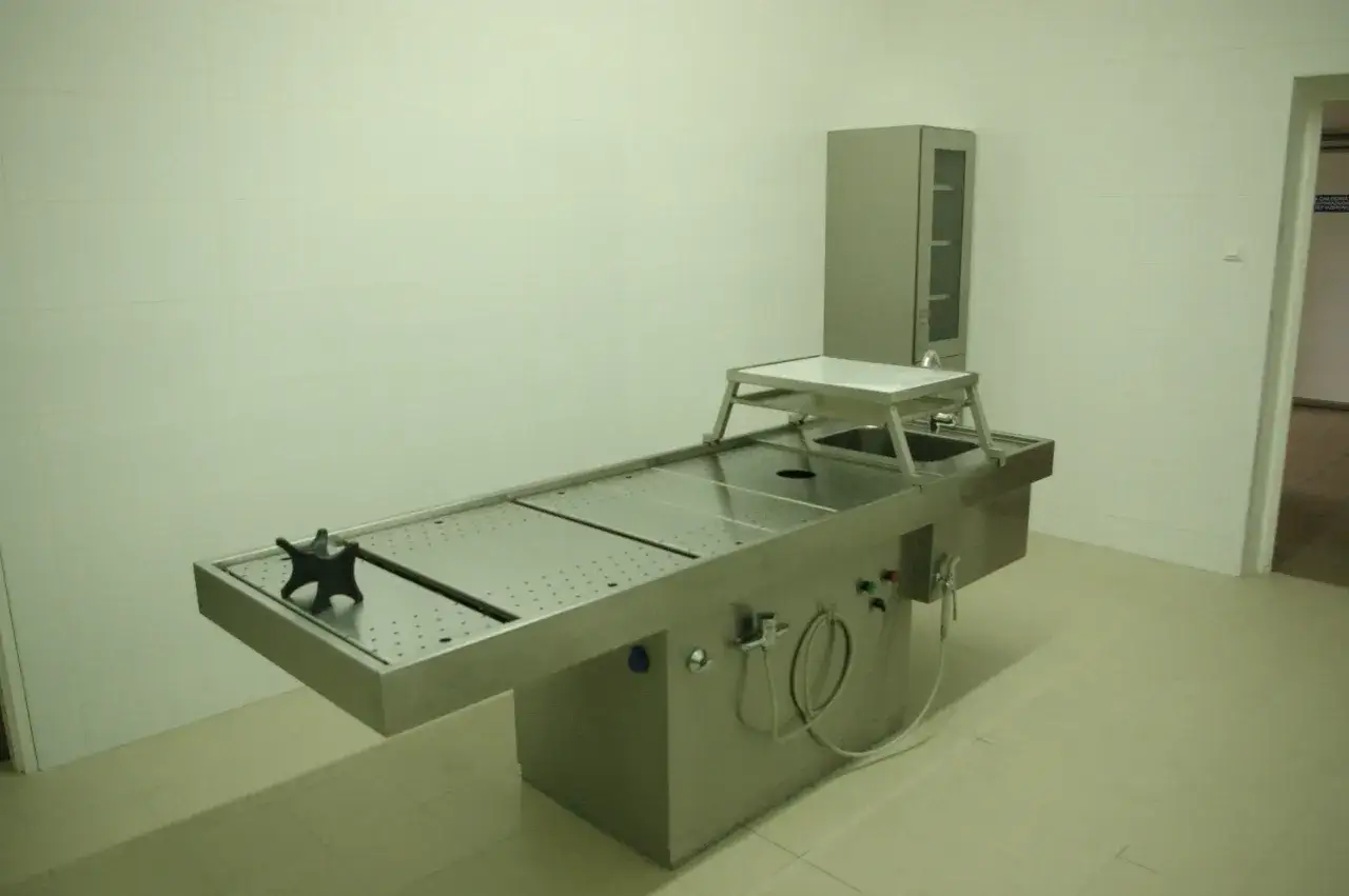 Stół sekcyjny w prosektorium, ze stali nierdzewnej, z umywalką i szafką.