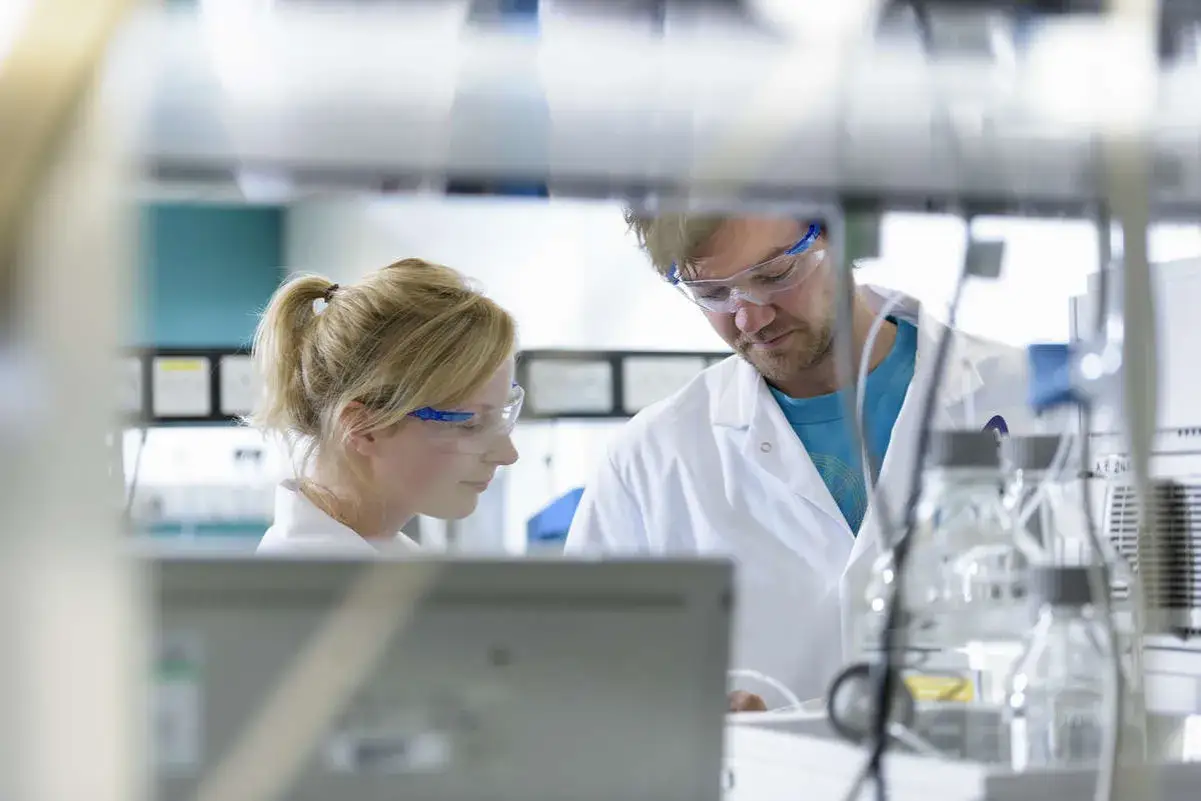 Naukowcy w okularach ochronnych pracują w laboratorium, być może nad szczepionką AstraZeneca.